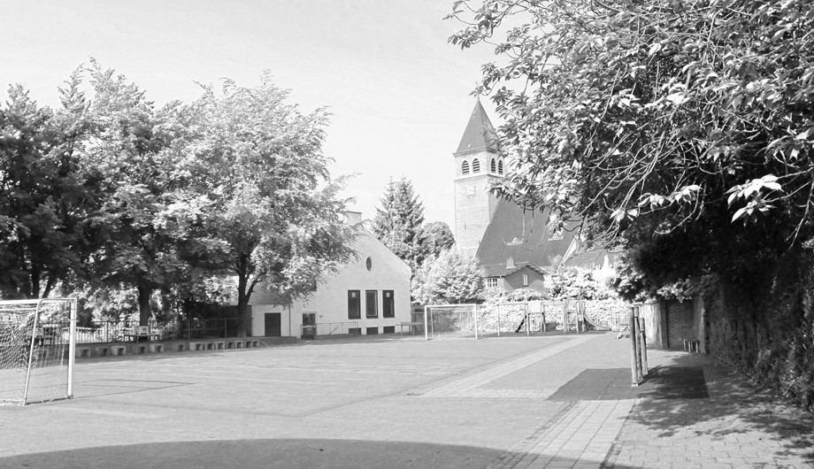 Blik op de speelplaats aan de achterzijde van het hoofdgebouw "de Klok", parochiekerk van Scharn en BSO Idefix..