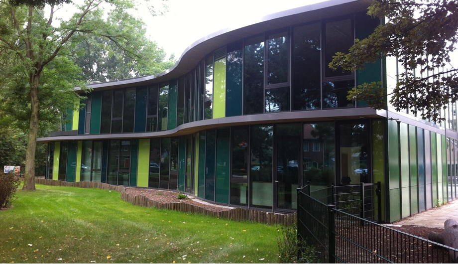 Het moderne gebouw van glas en metaal doet natuurlijk aan door de ronde vormen en de groene panelen.