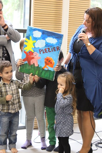 Kinderen onthullen kunstwerken over de kernwaarden tijdens de heropening van de school. 