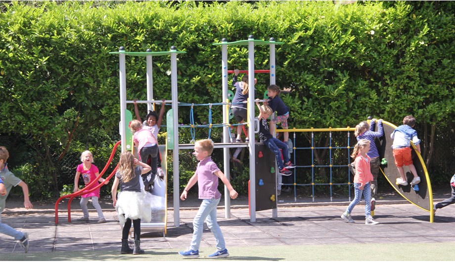 Het schoolplein biedt veel ruimte met daarin mooie speeltoestellen, maar ook een voetbalkooi.