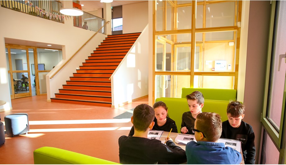 De ruime hal van basisschool De Waterloop biedt verschillende werkplekken waardoor samenwerking wordt gestimuleerd.